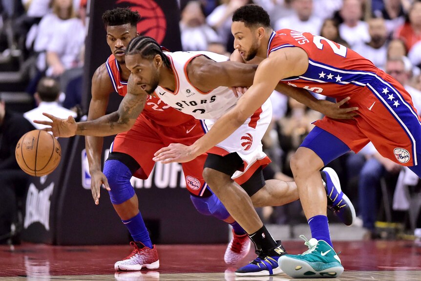 Ben Simmons, right in a red singlet, chases Kawhi Leonard, white singlet in centre, with Jimmy Butler, left, watching on