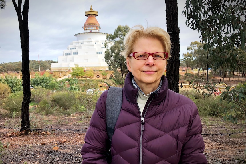 a lady with blonde hair stands in front of a temple