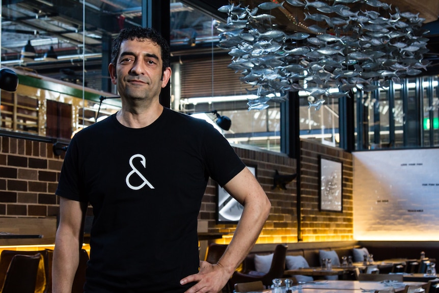 Sajad Akhlaghi inside a dining room with a hanging fish sculpture.