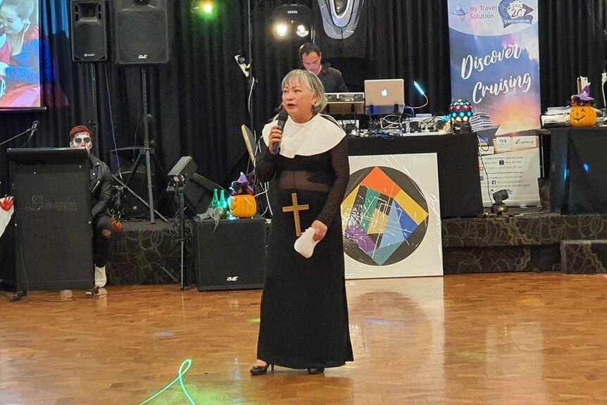 Terry Alpines wears a nun costume addressing a crowd at a Hallowwen event. 