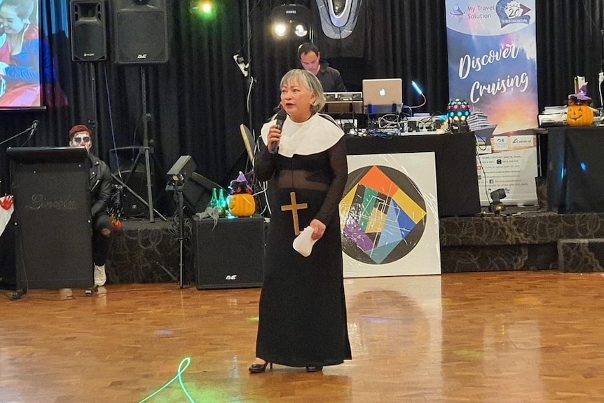 Terry Alpines wears a nun costume addressing a crowd at a Hallowwen event. 