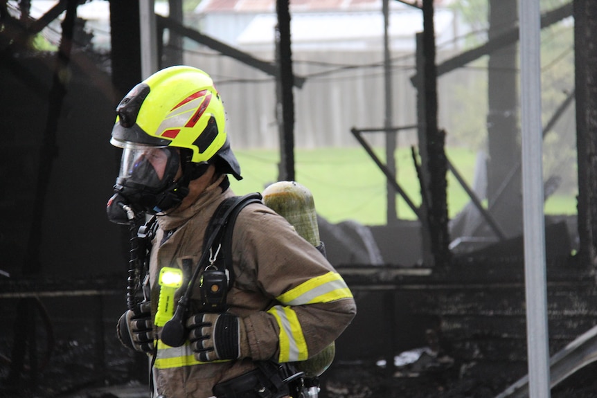 A Tasmania Fire Service crew member wearing breathing apparatus in front of a blackened classroom