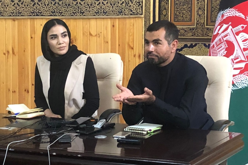 A man and women sit next to each other while speaking at a press conference.