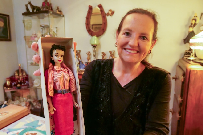 A woman wearing black holds a vintage Barbie#3