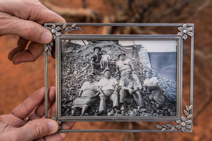 A man holding a black and white family photograph.