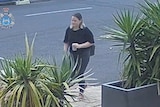 CCTV image of a woman standing in a carpark.