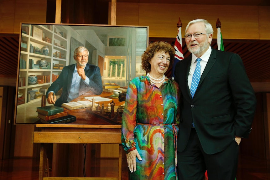Rudd and Rein stand smiling beside an oil painting of Mr Rudd.