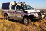 NT Police vehicle in remote Australia with desert and scrub in the background.