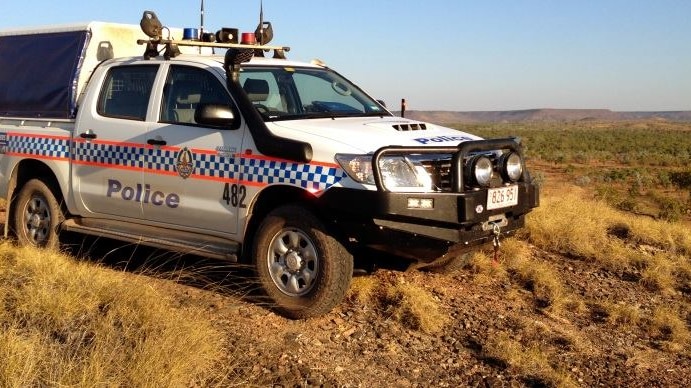 NT Police vehicle in remote Australia with desert and scrub in the background.