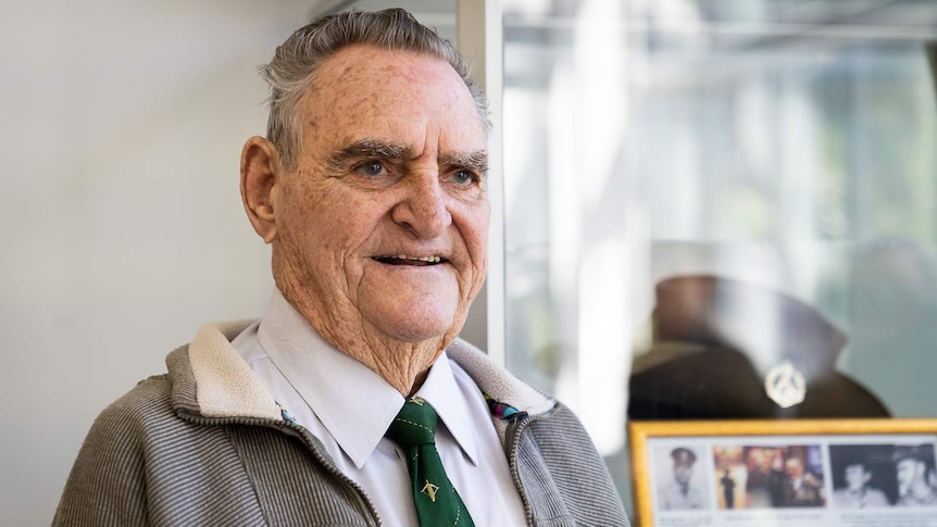 Man stands in front of Australian army hat in display cabinet