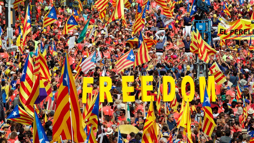 Thousands of people wave Catalan separatist flags and hold up letters spelling out the word "Freedom".