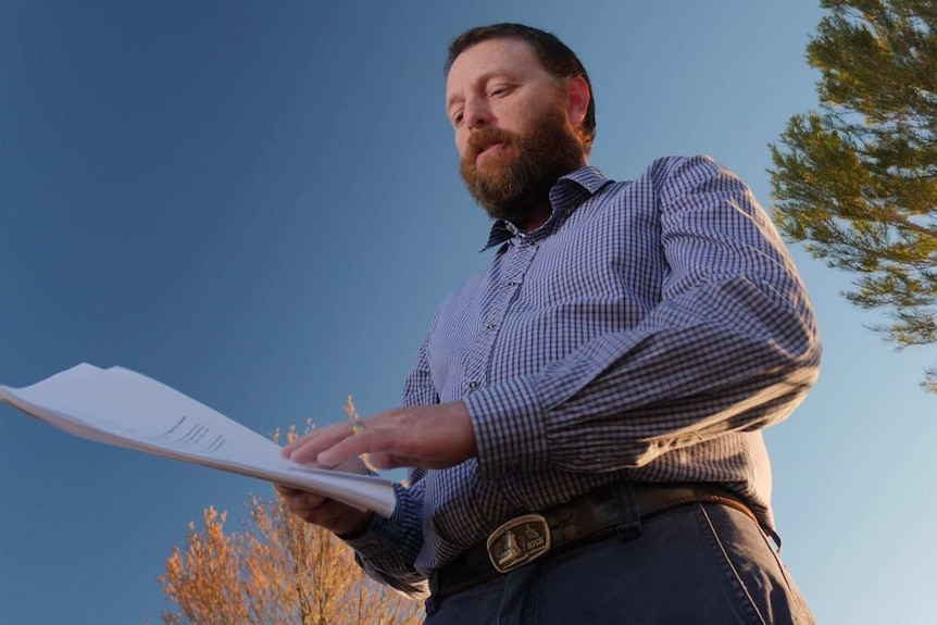 Mark Pierce looks over documents near the site overlooking where the solar panels will go