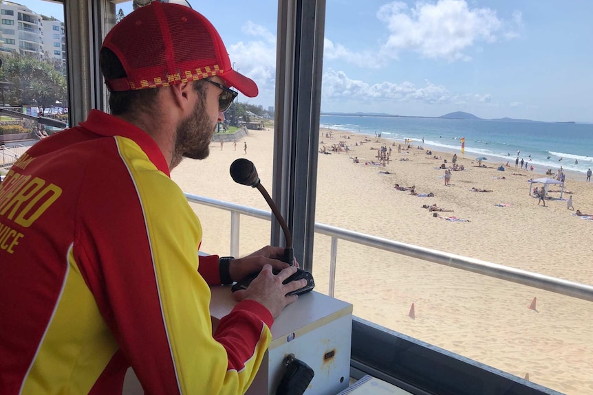 A lifesaver looking down at people on a beach in calm conditions