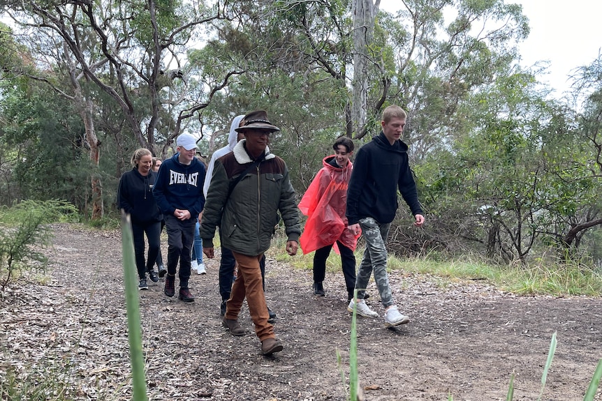 A group of teenagers walking in the bush with Uncle Gavi Duncan