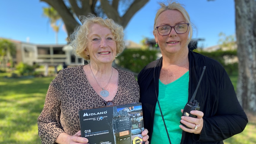 Two women hold a radio