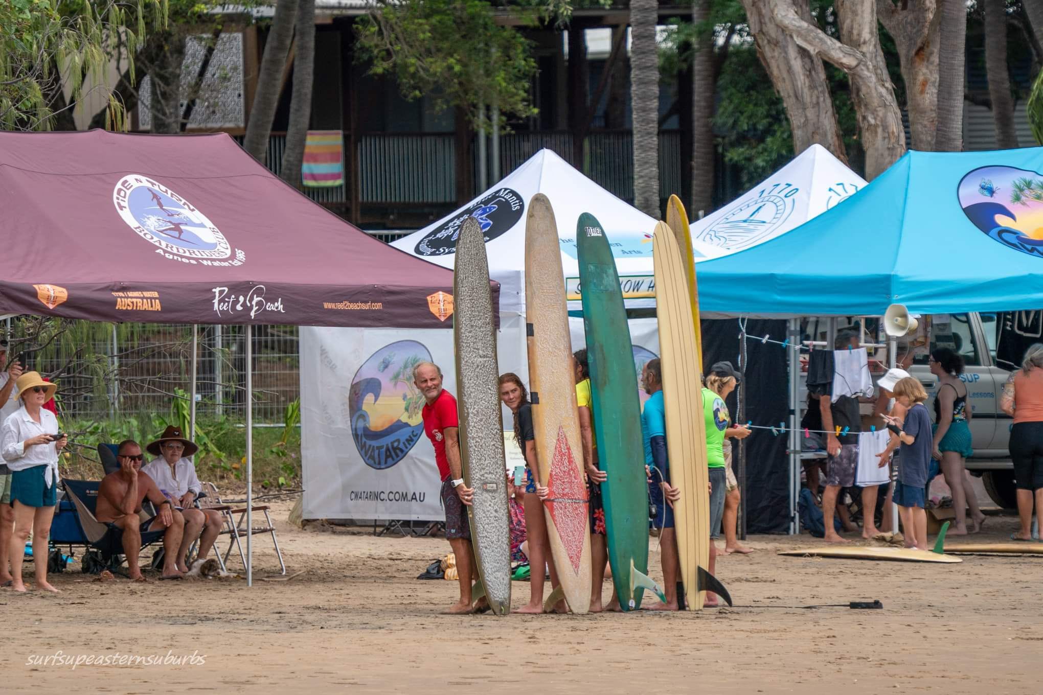 Hombres con tablas largas parados en la playa