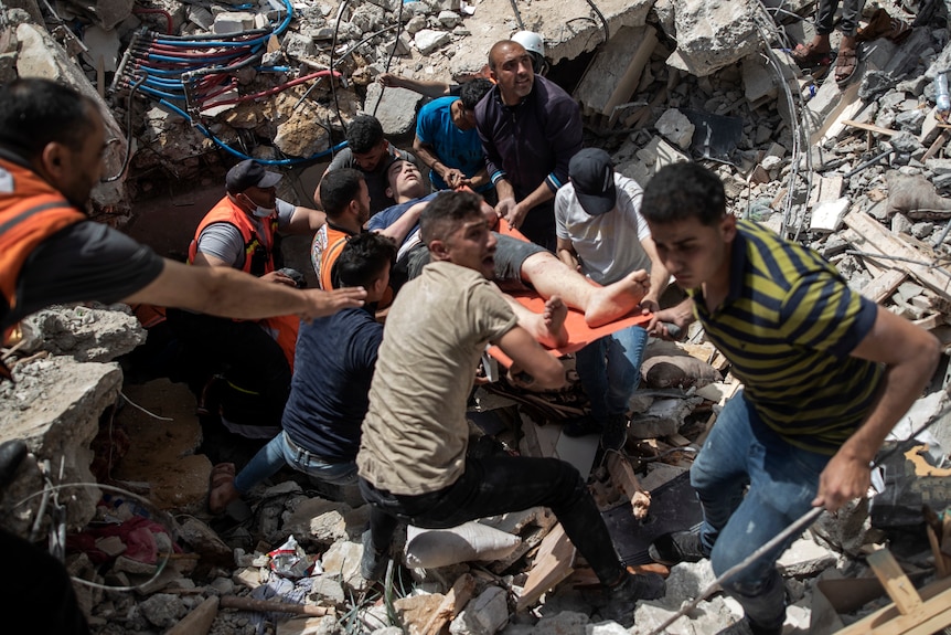 Palestinians rescue a survivor from under the rubble of a destroyed residential building