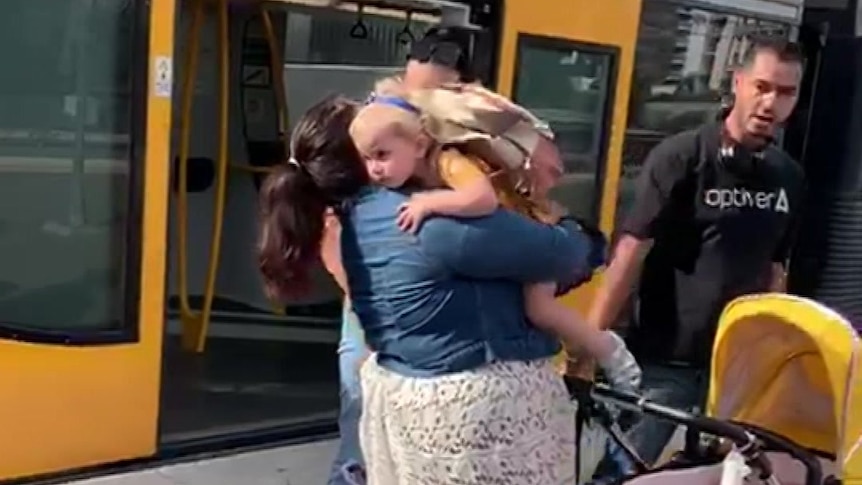 A mother and child hug on a train platform