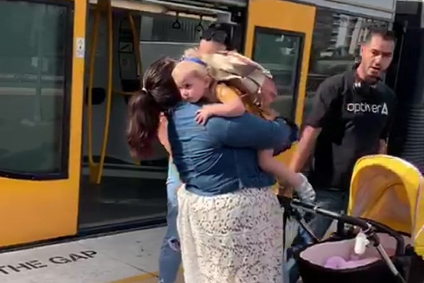 A mother and child hug on a train platform