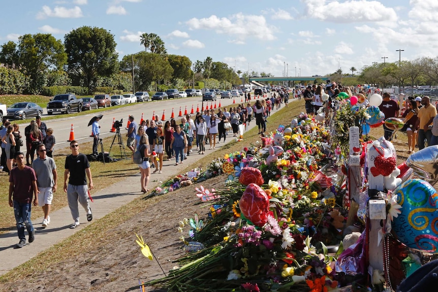 Parents and students walk past a memorial for the victims of the Florida school shooting.