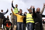 Anti-government protesters make victory signs as they stand on an army tank in Benghazi