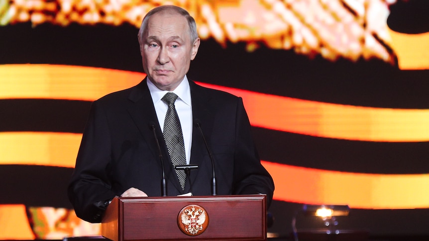 Vladimir Putin delivering speech at lectern.