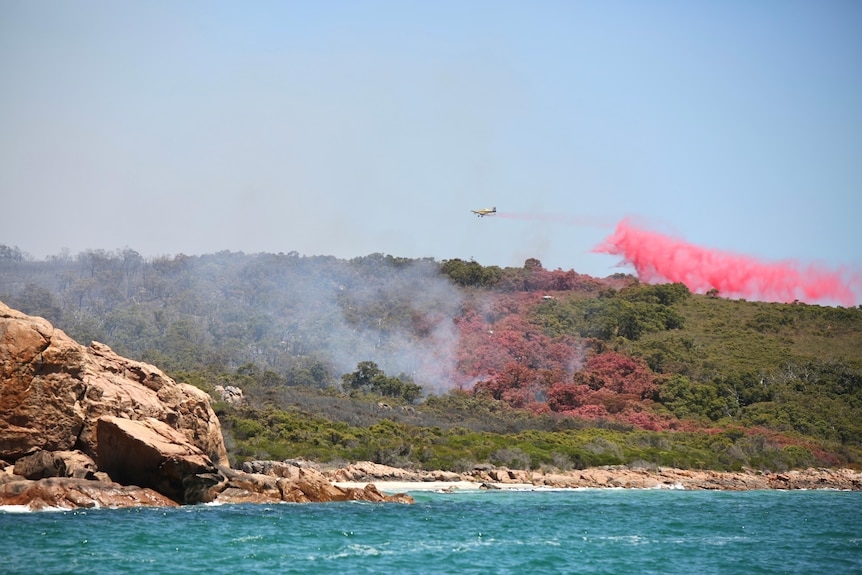 A water bomber is dropping retardant onto Eagle Bay