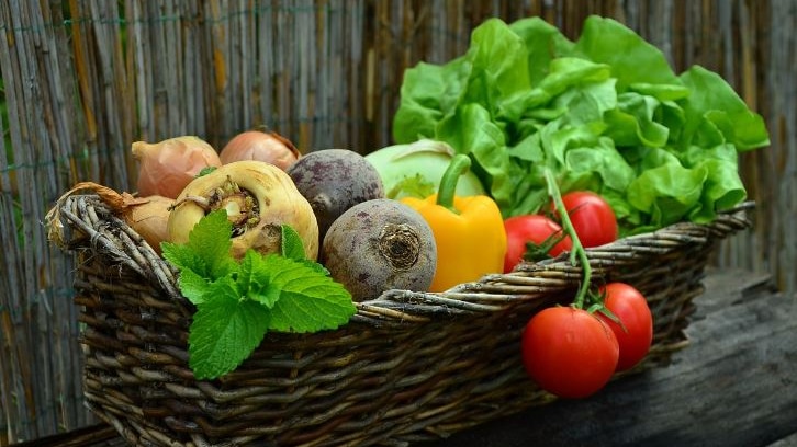 Picture of a basket full of vegetables, including tomato and capsicum