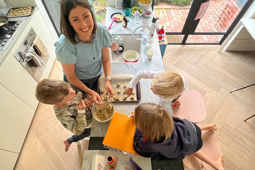 An overhead shot of a mother at a kitchen bench with three children