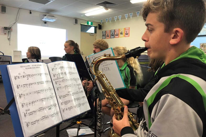 A male student plays a saxophone in class at a primary school