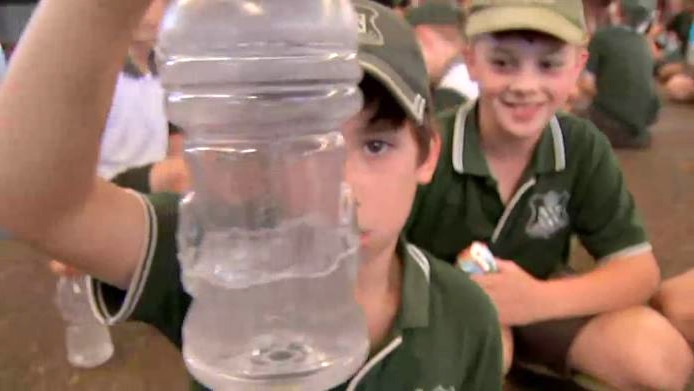 A student holds up a bottle partially full with water that he uses in the bottle flipping craze.