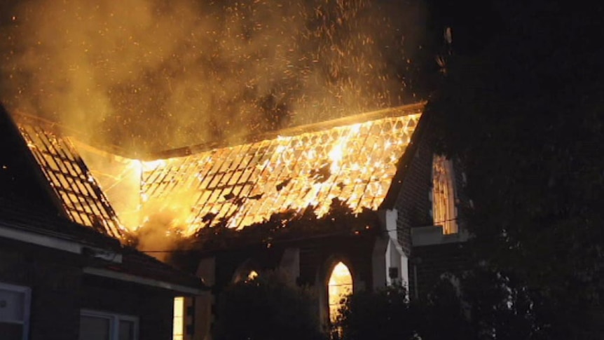 Night time image of fire burning inside the mosque, visible where the roof has collapsed.