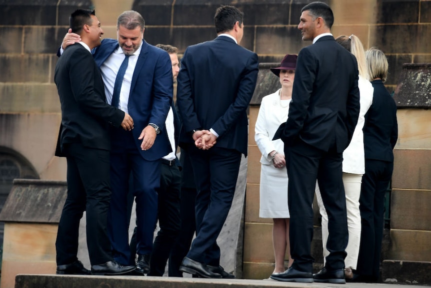 A group stands around hugging outside a church.