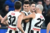 Nick Daicos is swamped by teammates after kicking a goal