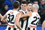 Nick Daicos is swamped by teammates after kicking a goal