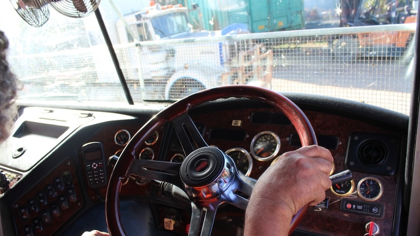 A man's hands on a steering wheel.