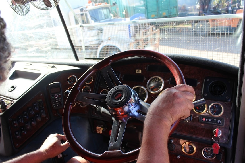 A man's hands on a steering wheel.