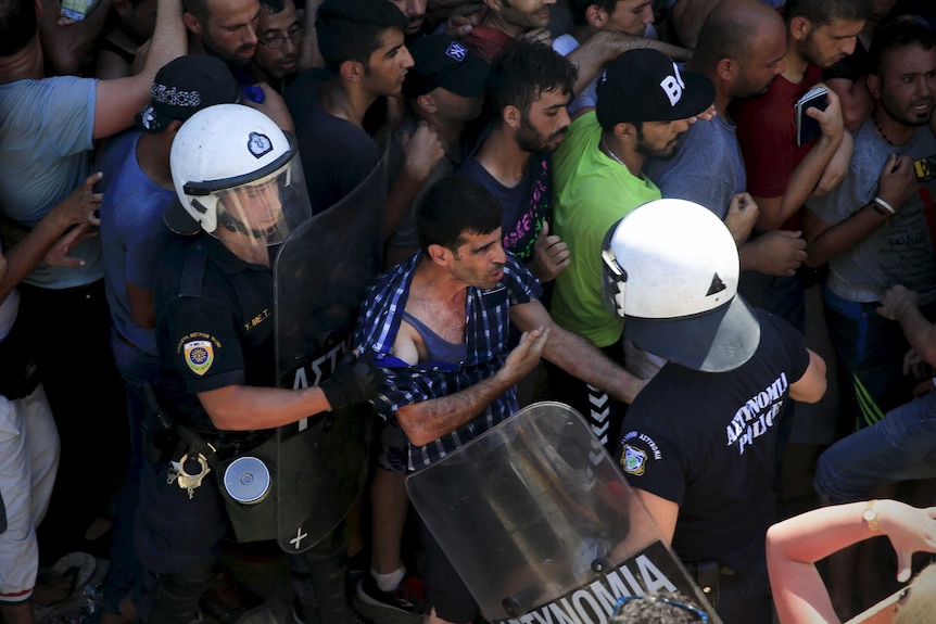 A migrant argues with a riot police officer on the Greek island of Kos