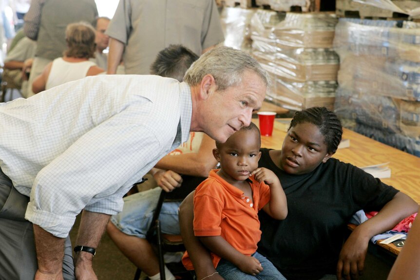 George Bush leans over to talk to a mother and child at a hurricane relief centre