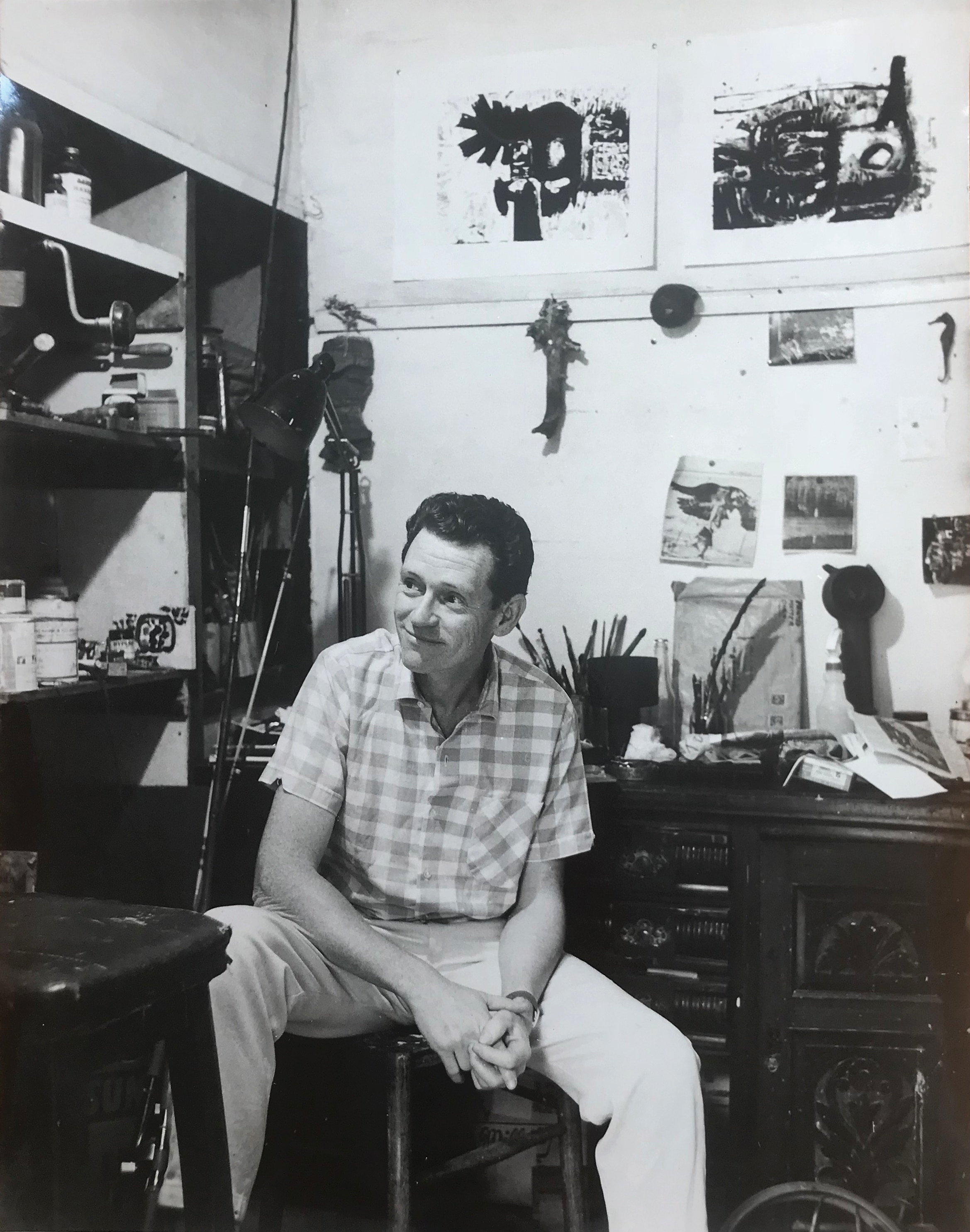 A black and white photo of the painter Guy Warren in the 60s, in his studio