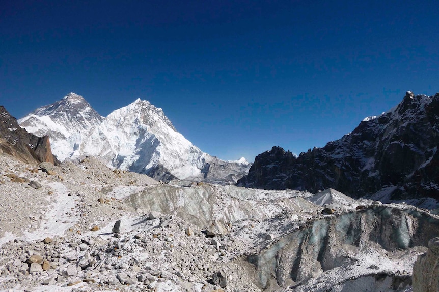 Rocky debris covering a glacier zone, with mountain peaks in the background.