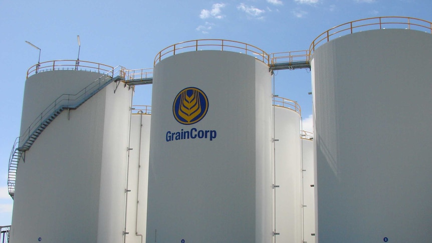 Large white silos with a ladder and walkway over the top, and a GrainCorp symbol and banner