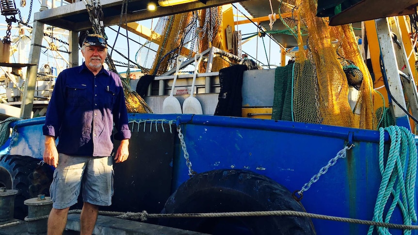John Palmer stands in front of a prawn trawlers, nets behind him, in Darwin