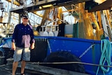 John Palmer stands in front of a prawn trawlers, nets behind him, in Darwin