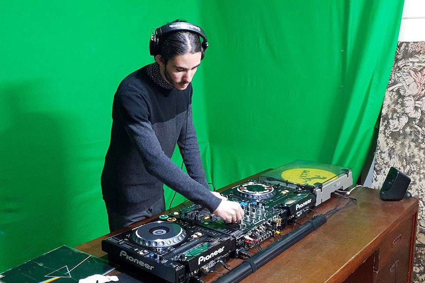 Joshua Lipovic stands at a table with record equipment on it.