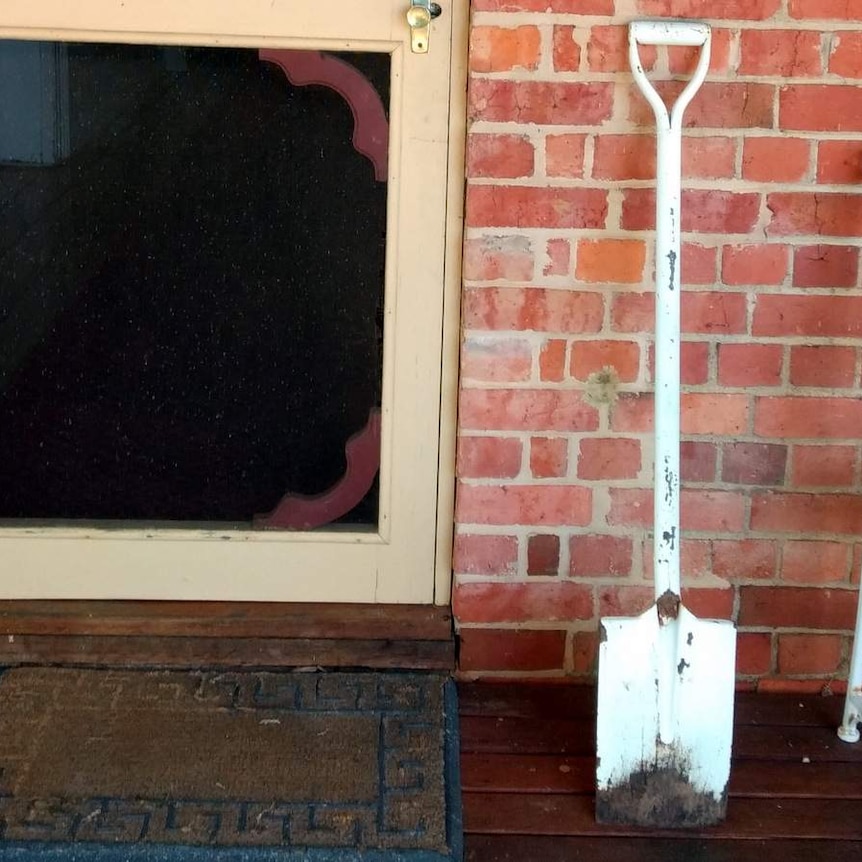 Shovel up against a door frame next to seat.
