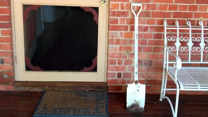 Shovel up against a door frame next to seat.