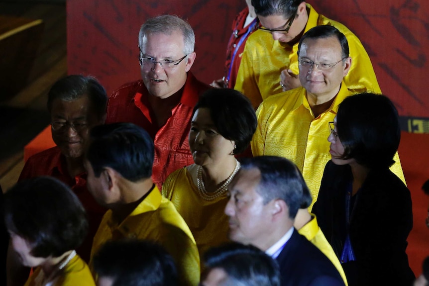 Scott Morrison in a red silk shirt, with other leaders in similar yellow and red silk shirts, mid stride