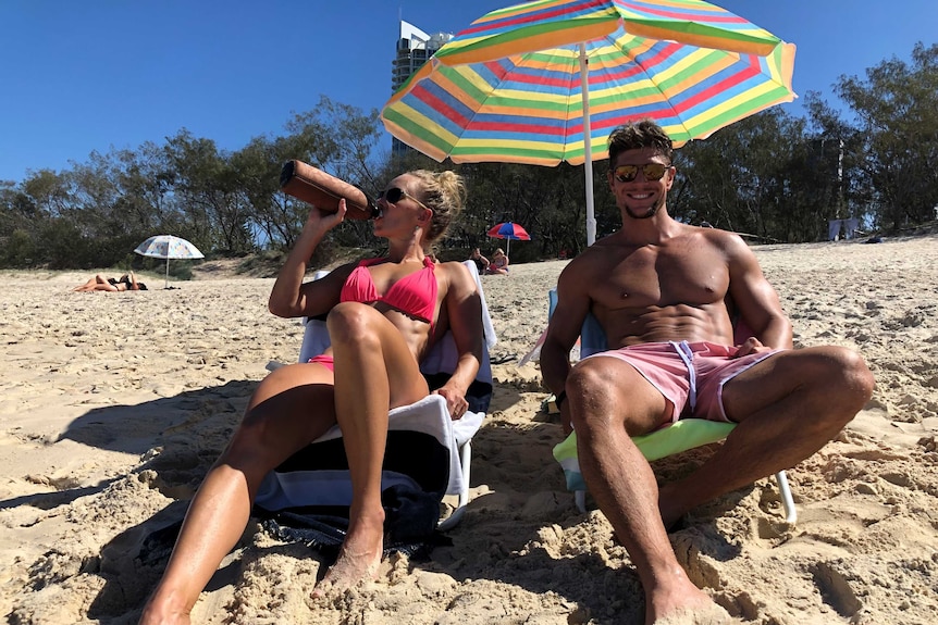 A man and a woman sit in fold up chairs on a beach