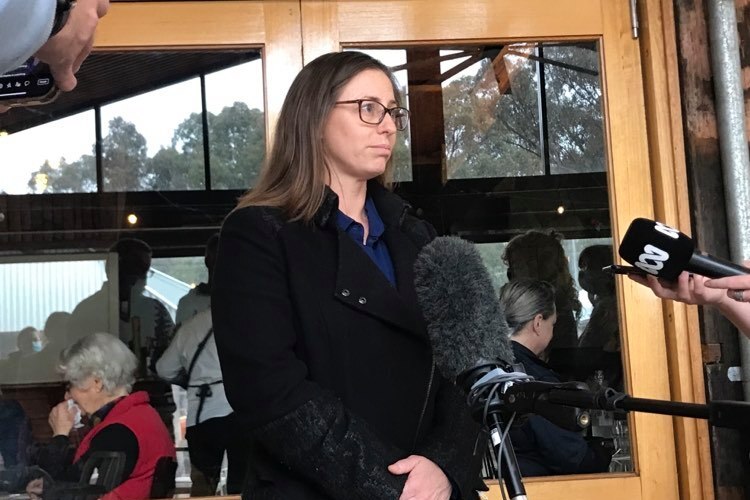 A woman stands outside a restaurant and talks to media